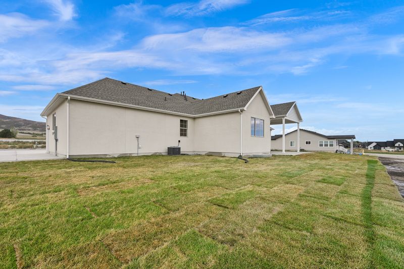 Rear elevation and the back lawn, with neighbouring homes and open fields beyond