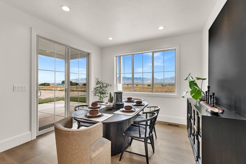 Dining area with a sliding door onto the covered patio and windows across Cache Valley