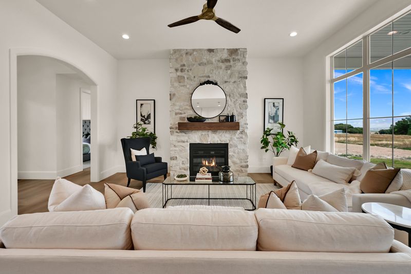 Great room with a floor-to-ceiling stone fireplace, timber mantel and a round mirror above