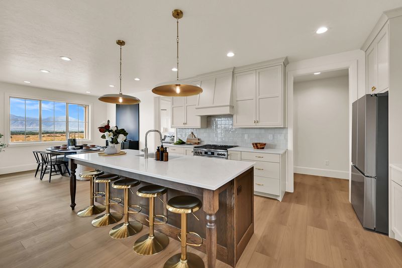 Kitchen with a walnut island seating four, white cabinetry and brass pendant lights