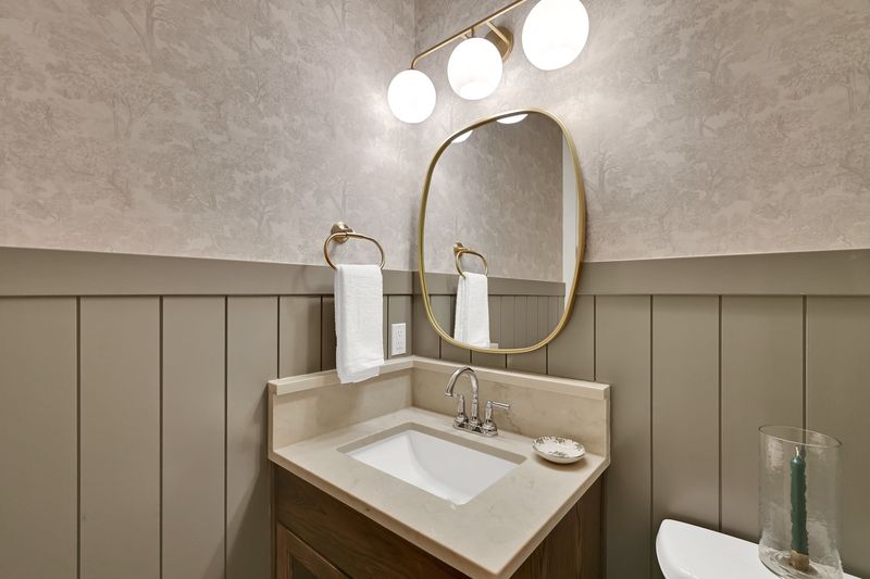 Powder bath with a panelled wainscot, plaster wall and a brass-framed mirror
