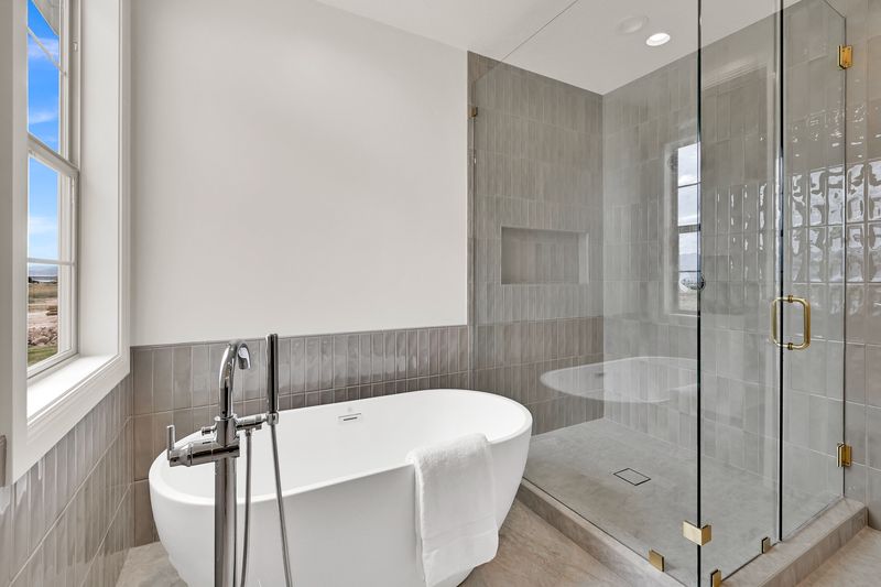 Freestanding soaking tub beside a fully tiled glass walk-in shower