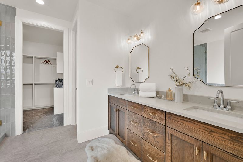 Double vanity in stained oak with brass fixtures and the walk-in closet beyond