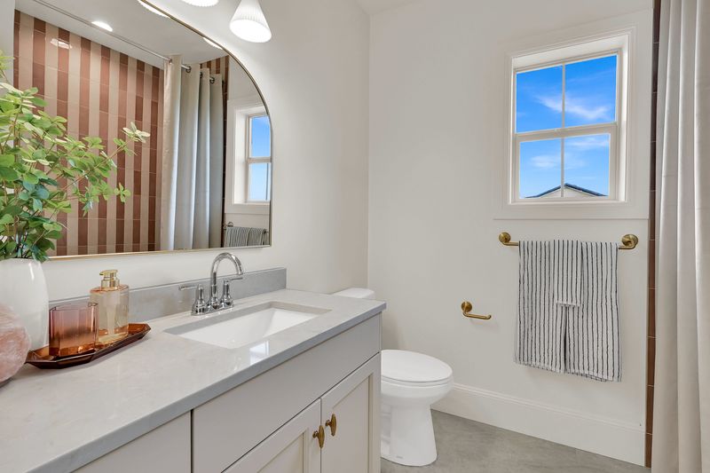 Secondary bathroom vanity with a quartz top and an arched mirror